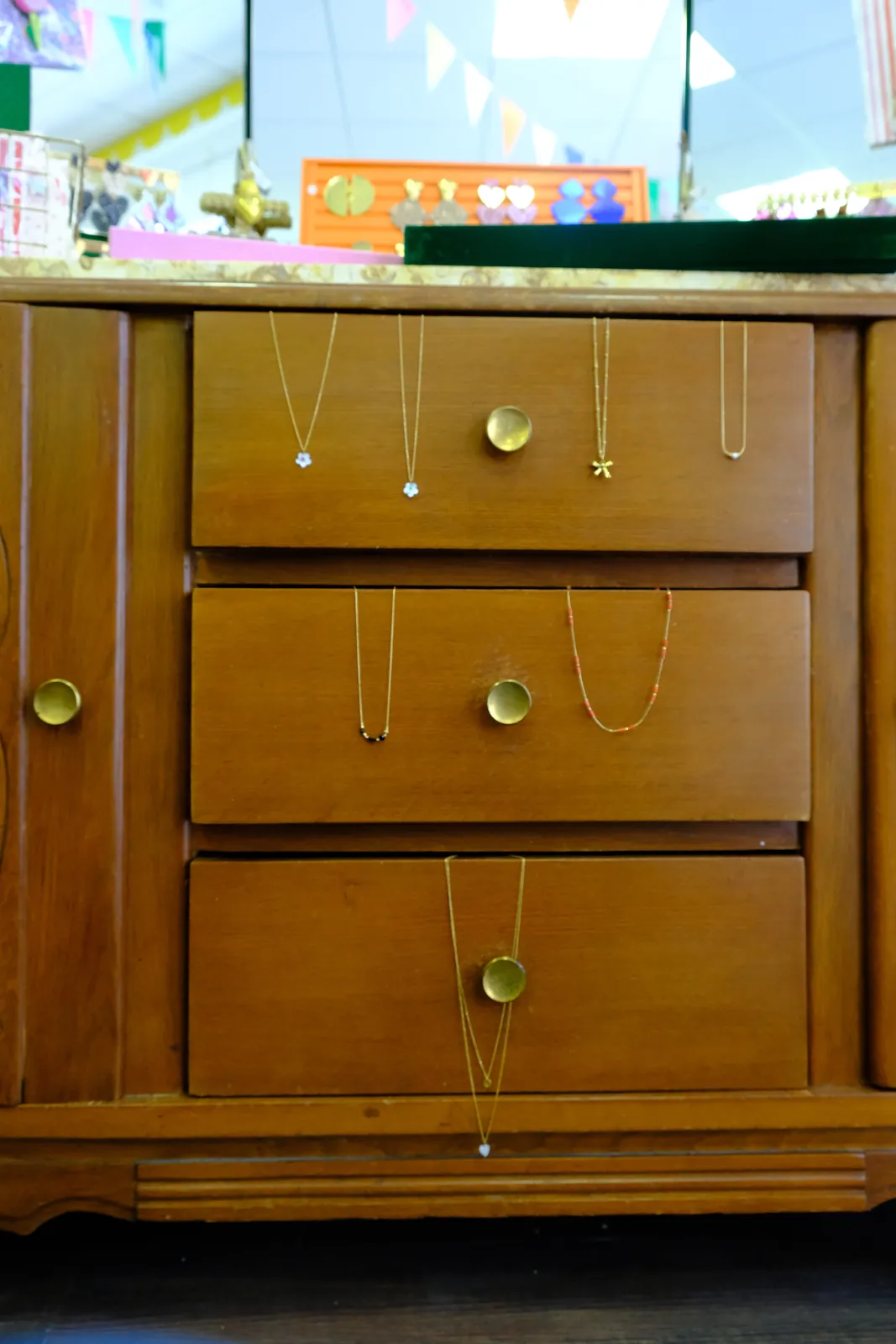 Colliers fins dorés présentés sur une commode vintage